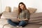 Image of relaxed affable woman with brown hair sitting on sofa i