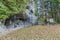 image of the replica of the Virgin of Lourdes in a natural grotto with a metal fence and a stone podium