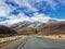 An image of a road in mountains with snow caps in New Zealand