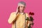 Image of romantic mature gentleman in yellow shirt with bowtie and suspenders, holds red roses, has problems, going for date or