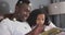 Image of roses over happy african american father and daughter reading book