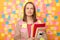 Image of sad upset woman wearing beige jacket posing over sticky notes to write reminder on yellow wall, holding paper documents,