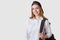 Image of school girl looking directly at camera with charming smile, poses isolated over white background with black bagpack,