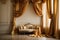 The image shows a luxurious living room with a plush velvet couch positioned under a canopy of gold curtains. The sunlight streams