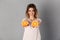 Image of Smiling woman in t-shirt giving oranges at camera