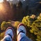 image of someone sitting on high area with bird\\\'s eye view looking down on the landscape below with a pair of legs in view