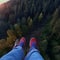 image of someone sitting on high area with bird\\\'s eye view looking down on the landscape below with a pair of legs in view