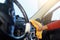 Image of steering, hands of man with orange rag washing interior of machine