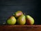 Image of Still Life with stack of green Pears. Dark wood background, antique wooden table