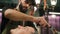 Image of stylish male barber washing hair of his client for making modern haircut in barbershop
