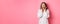 Image of surprised korean girl in dress, female model staring at camera and gasping amazd, standing over pink background