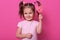 Image of sweet beautiful female child holding big lollipop candy, looks happy and excited  over pink background, little