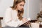 Image of thinking caucasian woman making notes and drinking tea