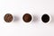 Image of three cups full of ground coffee, coffee beans and coffee on white background