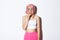 Image of timid cute girl in pink wig, looking indecisive and biting finger, standing over white background