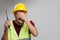 Image of upset builder man in yellow helmet with walkie-talkie on empty gray background.