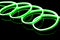 Image of vibrant spiral green neon glow sticks over black background with copy space