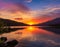 An image of a vibrant sunset over a serene lake, with colorful reflections shimmering