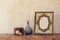 Image of victorian vintage antique classical frame, jewelry and perfume bottles on wooden table. filtered image
