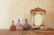 Image of victorian vintage antique classical frame and perfume bottles on wooden table. filtered image