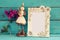 Image of white vintage blank frame and cute fairy princess on wooden table.