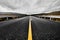 Image of a wide open prairie and mountains with a paved highway road stretching out as far as the eye can see with beautiful natur