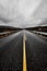 Image of a wide open prairie and mountains with a paved highway road stretching out as far as the eye can see with beautiful natur