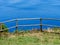 Image of wodden fence in front of a cliff with coast and sea in the background