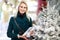 Image of woman with gift in box of white Christmas tree in store.