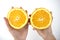 Image of woman`s hands holding two halves of fresh orange on  white background
