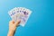 Image woman`s hands which holds British pounds in her hands isolated over blue studio background