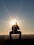 Image of woman`s silhouette performing gymnastics on a platform with sun rays