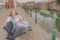 Image of a woman sitting on a bench next to a canal in the city of Ghent