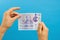 Image womans hands which holds British pounds in her hands isolated over blue studio background