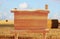 Image of wooden sign in front of rural wheat field landscape.