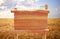 Image of wooden sign in front of rural wheat field landscape.