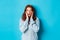 Image of young beautiful redhead girl, looking surprised, staring with complete disbelief at camera, standing in sweater