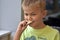 Image of young blond boy eating piece of potato chips looking happy