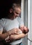 Image of young dad with cute little daughter in his arms. Father and newborn baby child indoor.