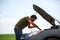 Image of young man mending broken car with open hood