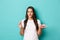 Image of young slim girl in white t-shirt, tempted to eat macaroon, holding cake, standing over blue background