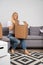 Image of young woman with cardboard box sitting on sofa