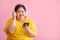 Image of a young woman with Down syndrome or a cerebral palsy student Listening to music and learning with a smart phone Pink