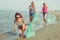 Image of young women volunteers picking up (cleaning) plastic garbage on the beach