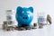 Images of stacking coins pile and blue smiling piggy bank to growing and savings with money box, Saving money for future plan and