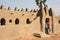 An imam stands at the entrance to a traditional mud-brick mosque in a village near Djenne, Mali