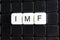 IMF title text word crossword. Alphabet letter blocks game texture background. White alphabetical letters on black