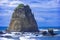 Immense rock formation in wavy seawater under a majestic cloudscape