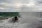 Immense waves hitting a large rock at the edge of the beach. Force of nature