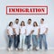 Immigration concept. Group of people standing near light wall